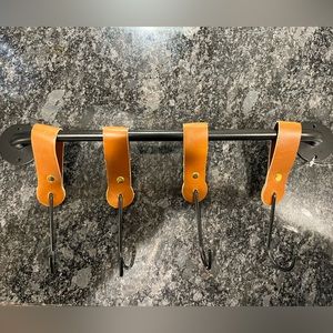 Black metal bar with hanging hooking with faux leather hanging straps.